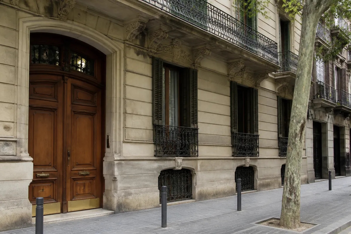 Façana de pedra i porta de fusta a l’Eixample de Barcelona, manyà urgent a la ciutat