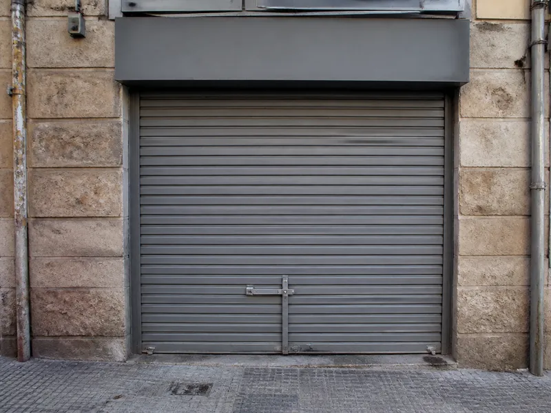 Persiana metálica gris cerrada en un local de Barcelona, reparación de cierres metálicos, sin rotulación